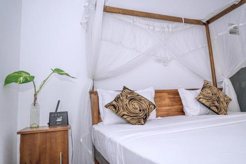 Un dormitorio con una cama con dosel con sábanas y almohadas blancas. en Stay Salty, en Matara