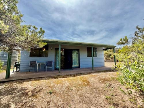 a small blue house with a porch with a table at Beachside Cabin No 2 at Island Beach in Island Beach