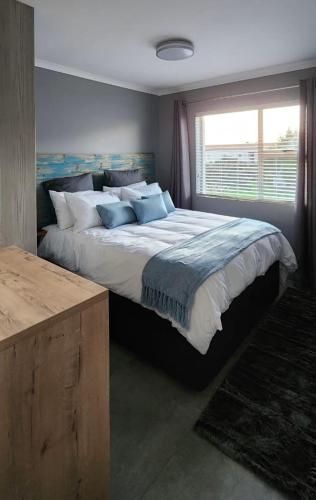 a bedroom with a large bed and a window at Tranquility - walking distance to beach in Langebaan