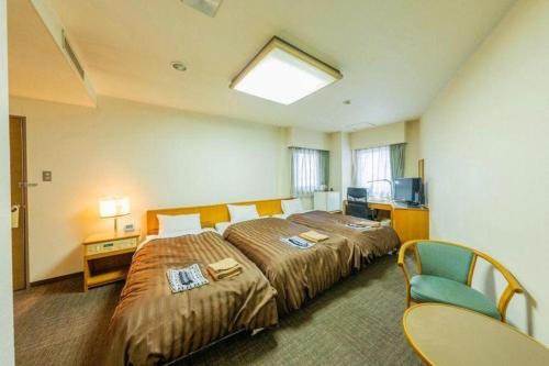 une chambre d'hôtel avec deux lits et une télévision dans l'établissement Mimatsu Hotel, à Mito