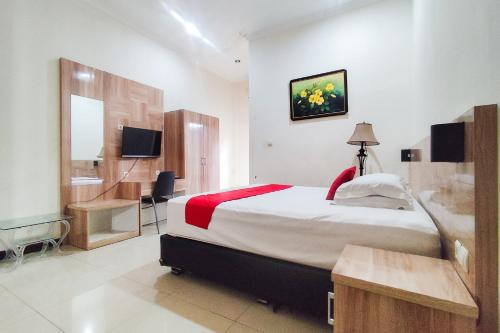 een slaapkamer met een bed, een bureau en een televisie bij RedDoorz near Tugu Bandara Sulthan Thaha Jambi in Sultan Thaha Airport