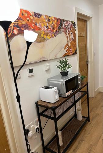 a table with a microwave and a lamp and a painting at Espaço Realeza in London