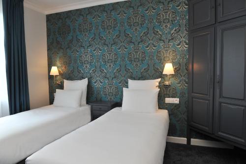 two beds in a room with green wallpaper at Mercure Paris Saint Cloud Hippodrome in Saint-Cloud