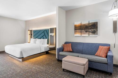 a hotel room with a bed and a couch at Brentwood Suites Nashville, an Ascend Collection Hotel in Brentwood