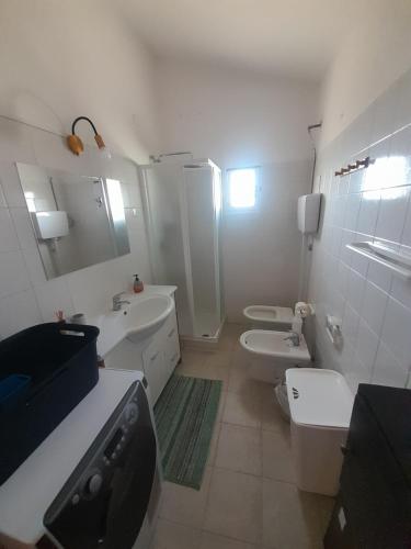a white bathroom with two toilets and a sink at Appartement à 300 m de la mer in Nughedu Santa Vittoria