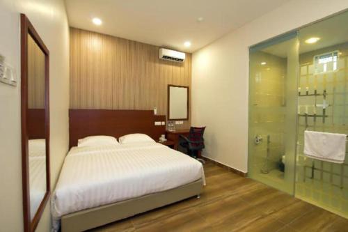 a bedroom with a bed and a glass shower at Elegant Hotel in Kampong Linau