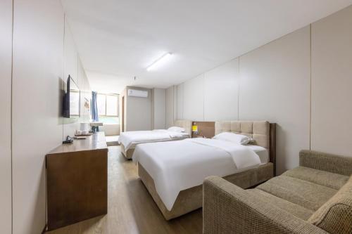 a hotel room with two beds and a couch at Baiyuan Hotel Changgang Baogang Avenue Metro Station Branch in Guangzhou