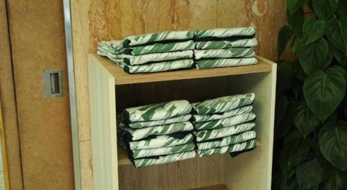 a stack of green and white towels on a shelf at Sanside Hotel in Kobe