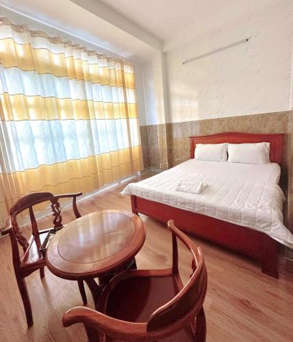 ein Schlafzimmer mit einem Bett, einem Tisch und Stühlen in der Unterkunft Nhà Nghỉ Quỳnh Thoa in Mỹ Tho