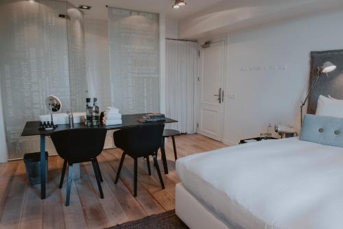 Boutique Hotel MANNA - Quality Lodgings في نايميخن: غرفة نوم بها سرير وطاولة وكراسي