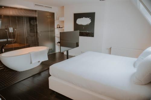 Boutique Hotel MANNA - Quality Lodgings في نايميخن: غرفة نوم بسرير ابيض وحوض استحمام