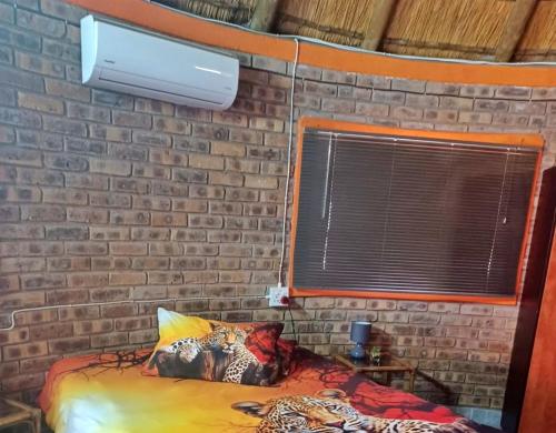 Bett in einem Zimmer mit Ziegelwand in der Unterkunft Sunbirds at Kruger in Marloth Park