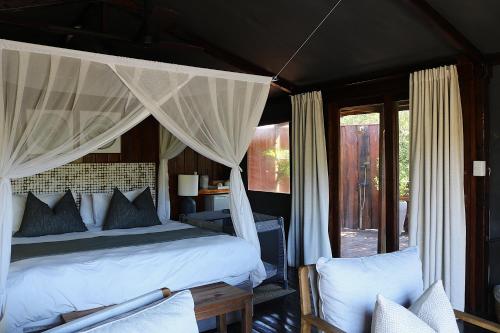 a bedroom with a bed with a canopy at Barefoot Addo Elephant Lodge in Addo