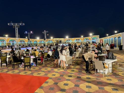 a group of people sitting at tables in a patio at night at Desert Safari Dubai Over Night Stay in Hunaywah