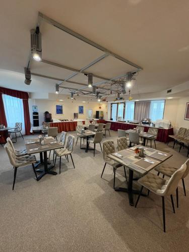 a dining room with tables and chairs and windows at Hotel Estella Superior in Eger