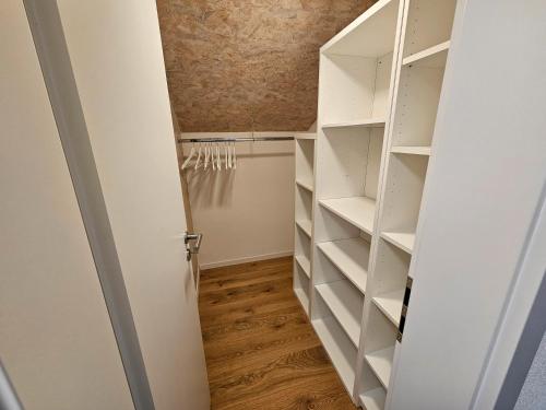 a walk in closet with white shelves and a door at Ferienwohnung Haldenblick in Weißensberg
