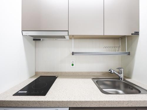 a kitchen with a sink and white cabinets at Elmomento Sasang in Busan