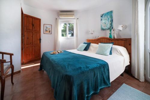 ein Schlafzimmer mit einem Bett mit einer blauen Decke darauf in der Unterkunft Villa Torre Xanchu in San Jose de sa Talaia
