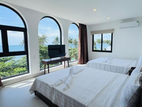a bedroom with two beds and a television and windows at Ripple house in Ấp Thiện Sơn