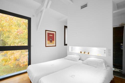 a white bedroom with a bed and a window at Loft Ôrizon - Domaine De L'ô in Bellacaud