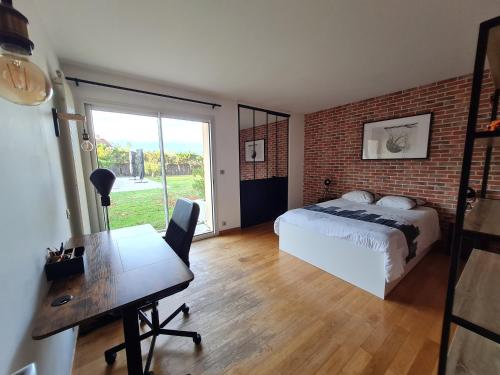 La BredeにあるLa Bredi Villa proche de Bordeaux avec piscine et spaのレンガの壁、ベッドルーム1室(ベッド1台、デスク付)