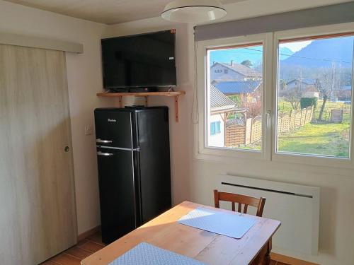 a kitchen with a refrigerator and a table and a window at Maison de Village au pied des montagnes in Randens