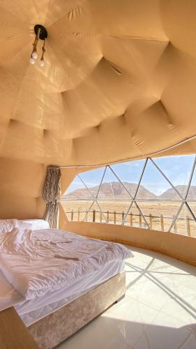 a bed in a room with a view of the desert at Wadi rum sky luxury in Disah
