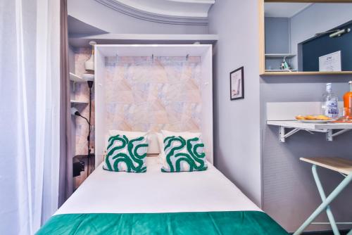 Bett in einem kleinen Zimmer mit grünen und weißen Kissen in der Unterkunft WS Jardin du Luxembourg - Boissonade in Paris