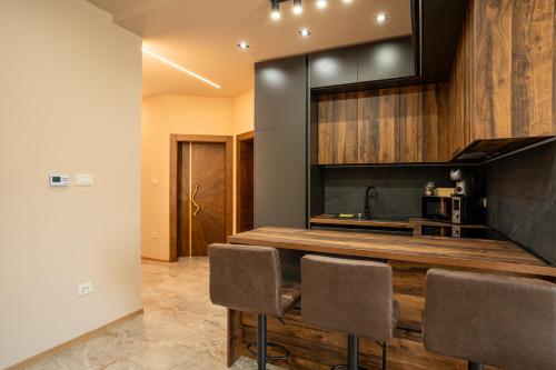 a kitchen with a counter and some chairs at Zsizell Lux Apartman in Kanjiža