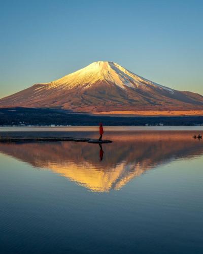 a man standing in the water in front of a mountain at FUJI Forest House203 in Gotemba