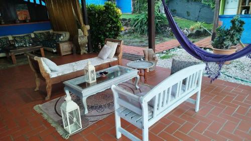 a patio with a hammock and a couch and chairs at Gîte au Carbet in Le Morne aux Bœufs