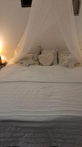 a white bed with white curtains and pillows at Gîte au Carbet in Le Morne aux Bœufs