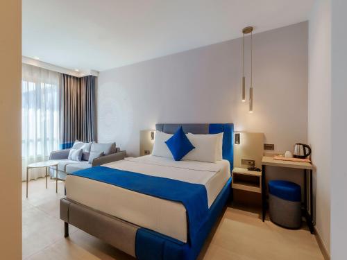 a bedroom with a blue and white bed and a couch at Echinus Blue Hotel in Antalya