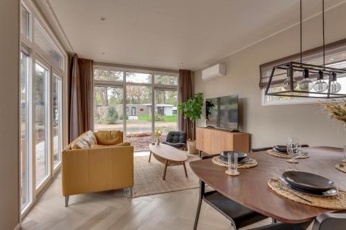 a living room with a wooden table and a dining room at Natuurhuisje Hellendoorn met luxe Hottub in Haarle