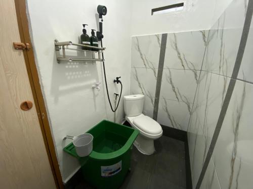 a bathroom with a toilet and a green trash can at BMC HomeStay in Sebungsungai