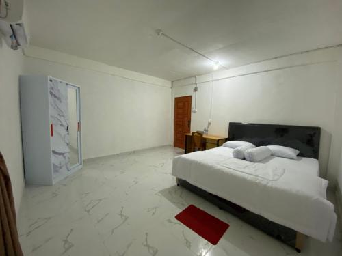 a white bedroom with a bed and a table at BMC HomeStay in Sebungsungai