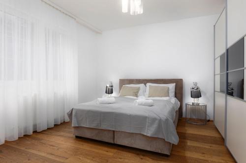 a white bedroom with a large bed with white curtains at Villa Hietzing in Vienna