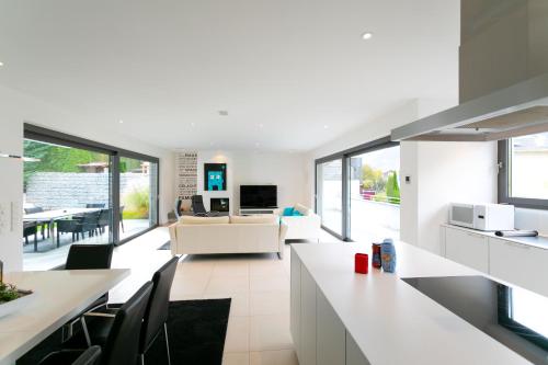 a kitchen and living room with white furniture and windows at Villa Shangrila - Alpstay in Naturno