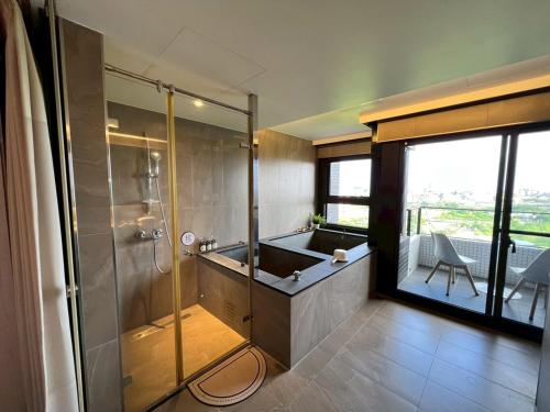 um banheiro com banheira e box de vidro em 漫遊文旅溫泉宅ㄧ山海景觀陽台房ㄧ晚上6點入住ㄧ晚進晚退一21小時睡飽飽方案 em Toucheng
