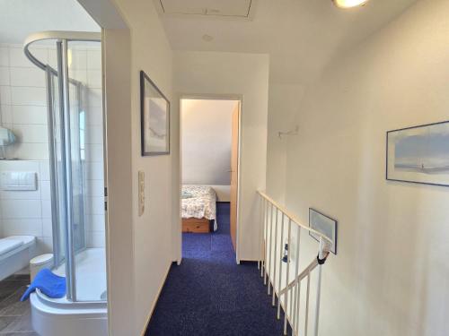 Nordseeferienhaus Ehlers في نيسمارزييل: ممر يؤدي الى غرفة بسرير وحمام