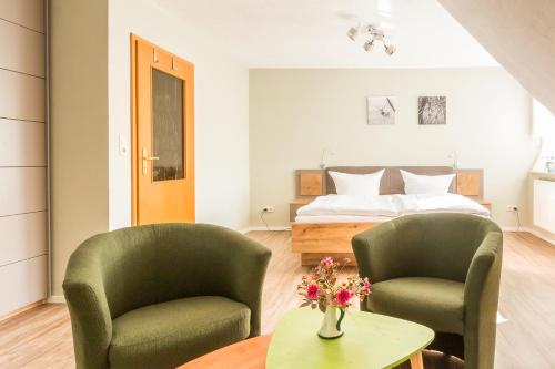 JagdhausにあるJagdhaus Schwinkelsmoorのベッドルーム1室(緑の椅子2脚、ベッド1台付)