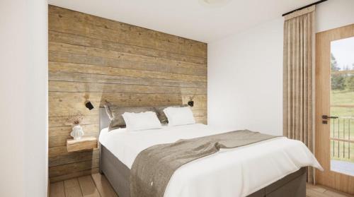a bedroom with a white bed and a wooden wall at Alpen Lodge Kirchberg in Kirchberg in Tirol