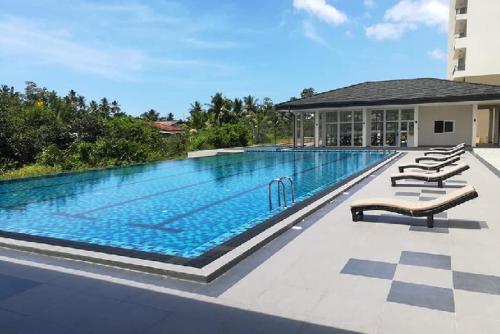 a large swimming pool with lounge chairs next to a building at Fairway Galle in Galle
