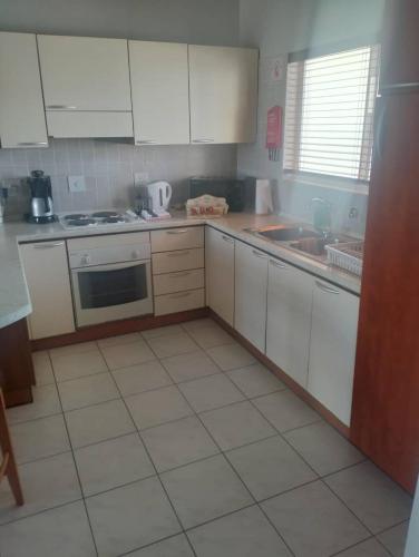 een keuken met witte kasten en een witte tegelvloer bij On the Beach 20 in Swakopmund