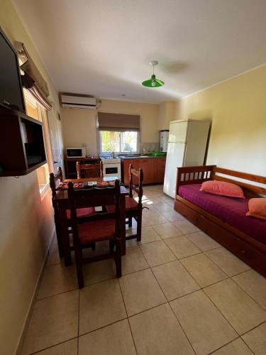 a living room with a table and a kitchen with a refrigerator at Cabañas Las Primorosas in Cañuelas
