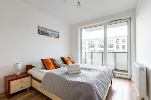 een witte slaapkamer met een bed en een groot raam bij Nasypowa Spacious Apartment by BookingHost in Gdynia