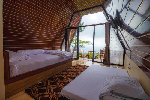 a bedroom with two beds and a large window at Khanzana Cabin and Camp in Kejajar
