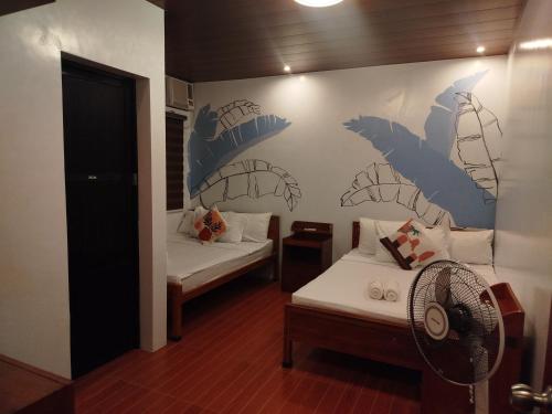 ein Zimmer mit zwei Betten und einem Ventilator in der Unterkunft BALAI MALINAWON - Villa 2 in General Luna