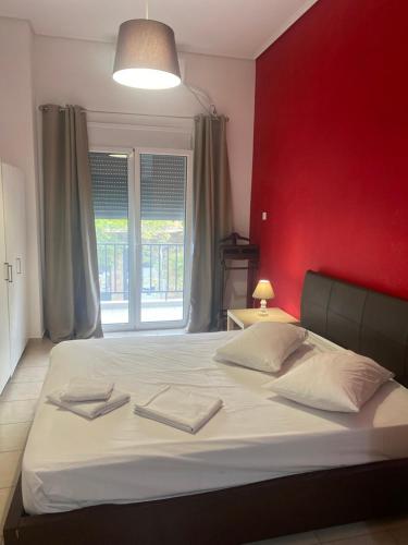 een slaapkamer met een groot wit bed en een rode muur bij Electra apartment in Thiva