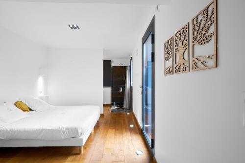 une chambre avec un lit blanc et un parquet dans l'établissement Loft Ôvebas - Domaine De L 'ô, à Bellacaud